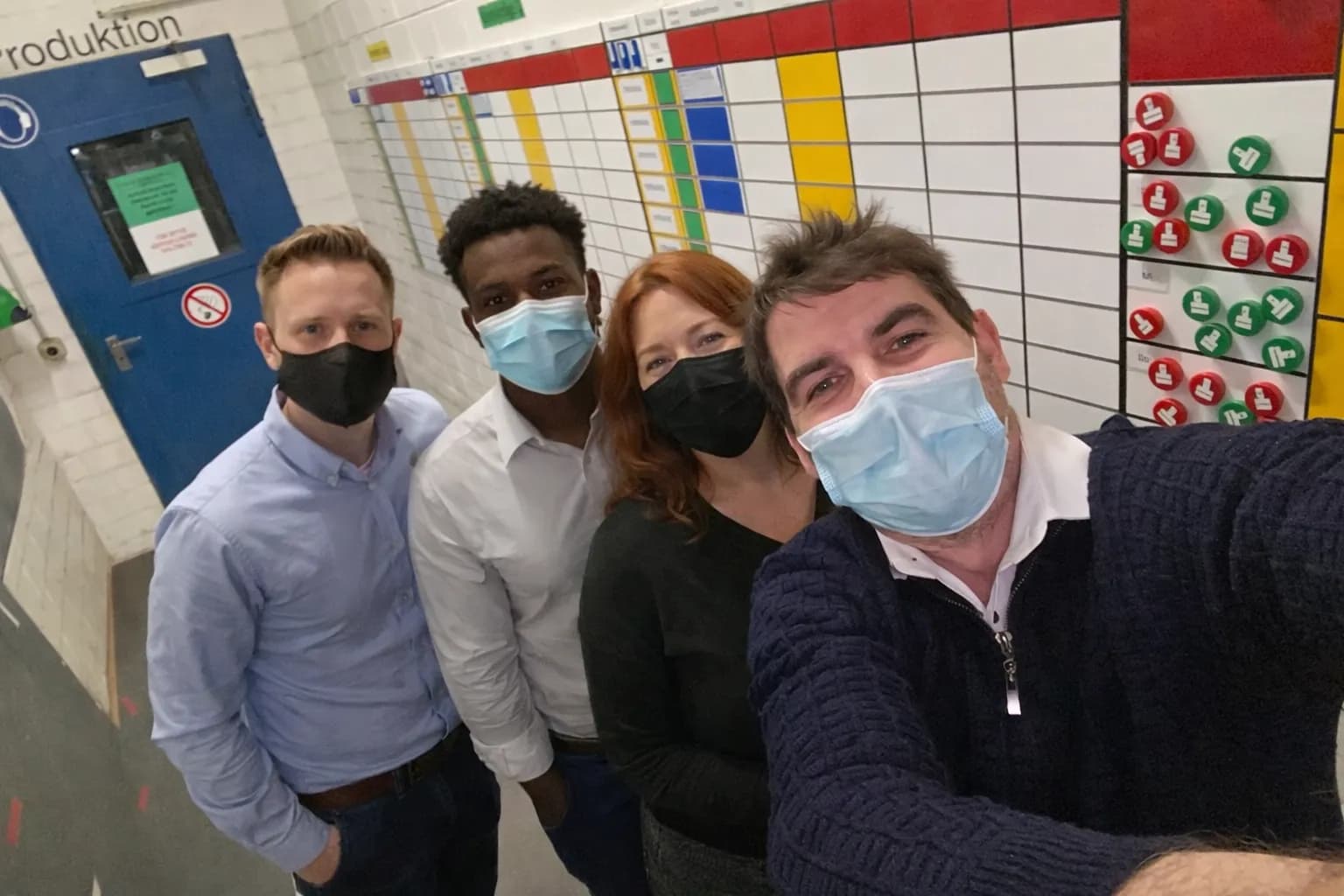 Team vor einem visuellen Steuerungsboard im Produktionsumfeld.